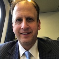 Headshot of a man in a gray suit and blue tie