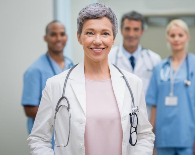 A doctor standing in front of three of her colleagues.