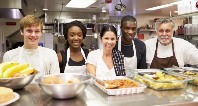 Five volunteers serving food for a nonprofit organization. 