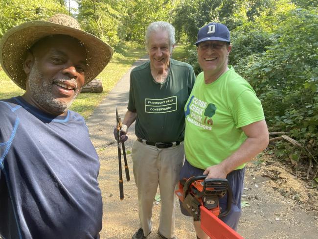 Three men standing on a path in a park